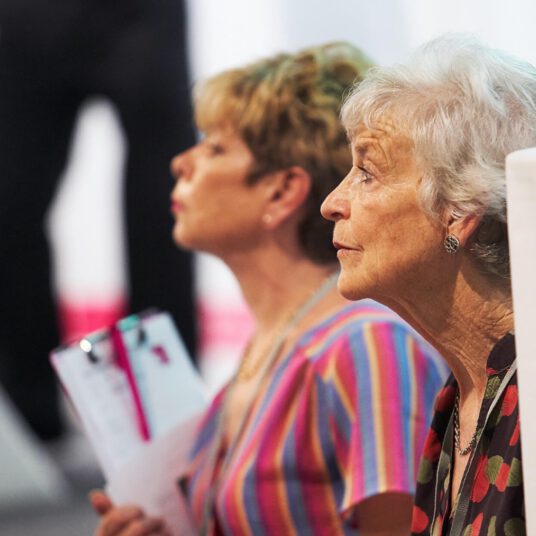 Two women watching at an auction